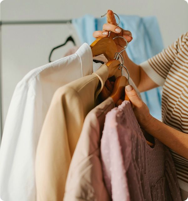 Woman stacking four clothes hangers with clothes on them